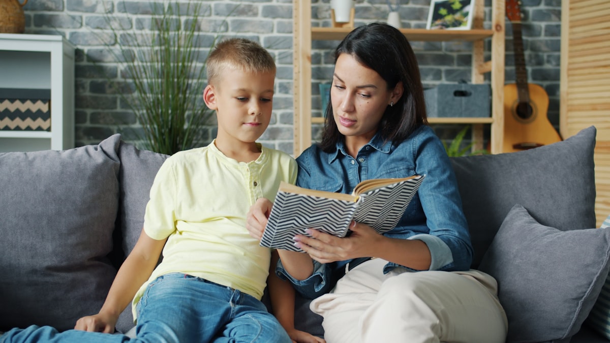 A parent reading and reviewing schoolwork together with their child at home