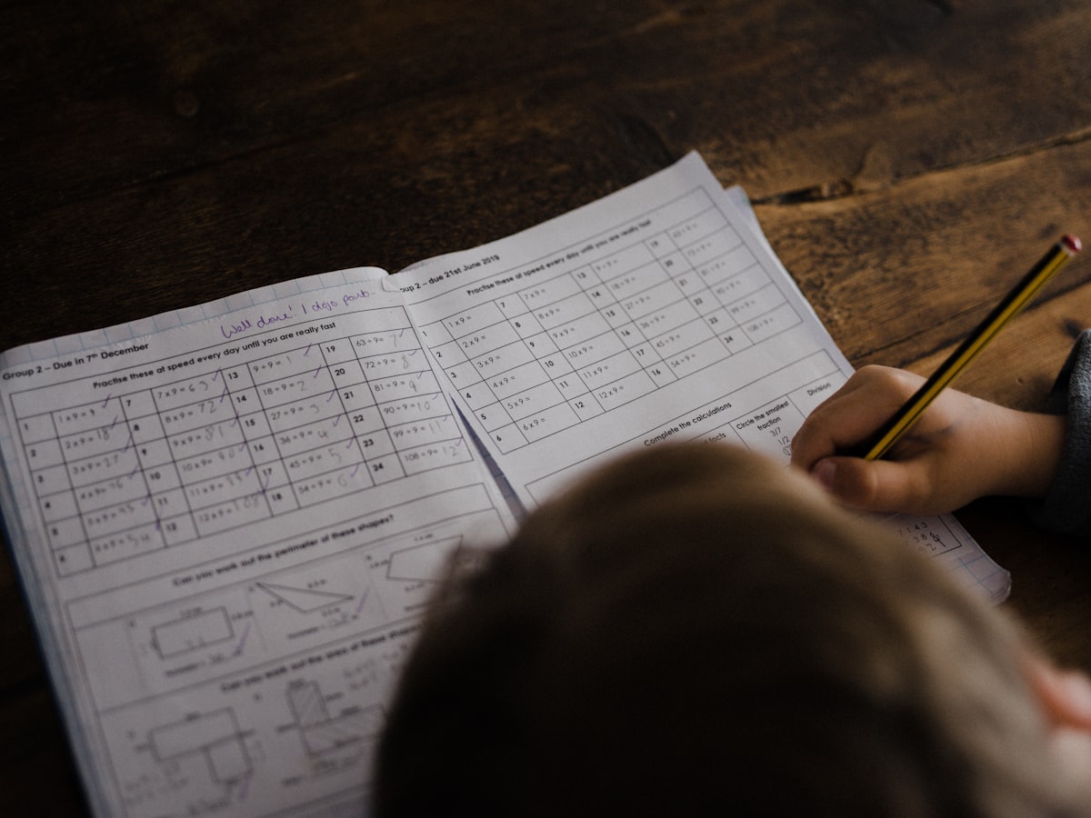 Close-up of a student's hand working through a math worksheet